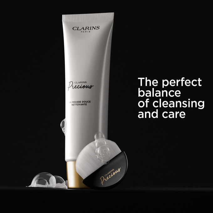 Clarins foam facial cleanser, showcased on a black background, accompanied by text detailing its cleansing and caring effects